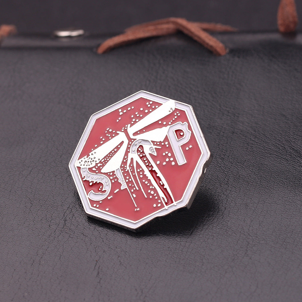 Broche de goteo de aceite con insignia M dorada